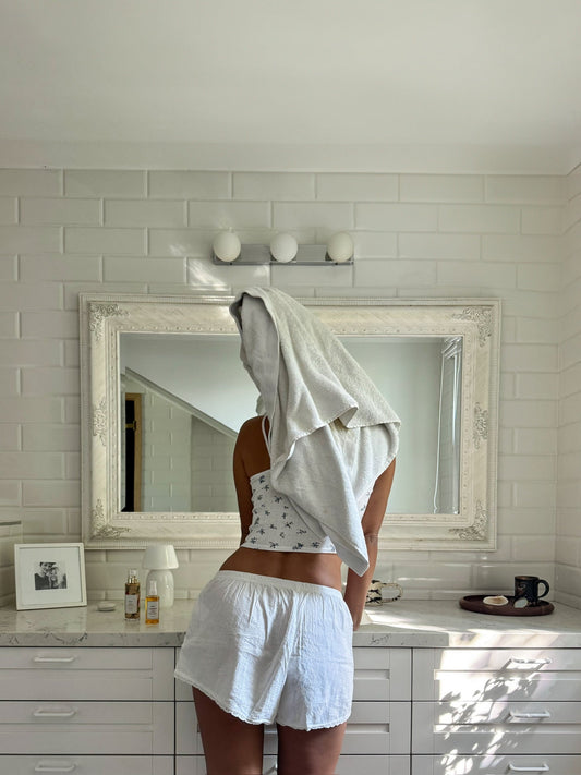 Woman after a shower in a bright bathroom, illustrating a skincare routine to protect dry skin from Cyprus hard water.